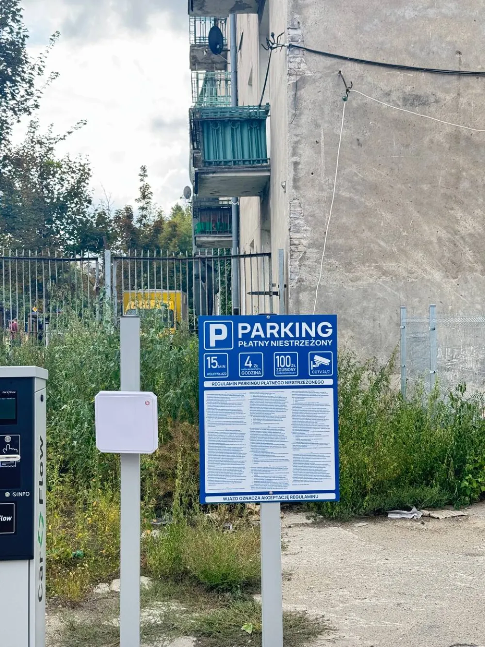 Niebieska tablica «PARKING PŁATNY NIESTRZEŻONY» przy wjeździe na parking